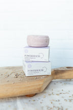 Two boxes of POWERHOUSE Lavender & Peppermint Hand Soap stacked on a wooden board, with one pale pink soap bar resting on top, against a bright white background.